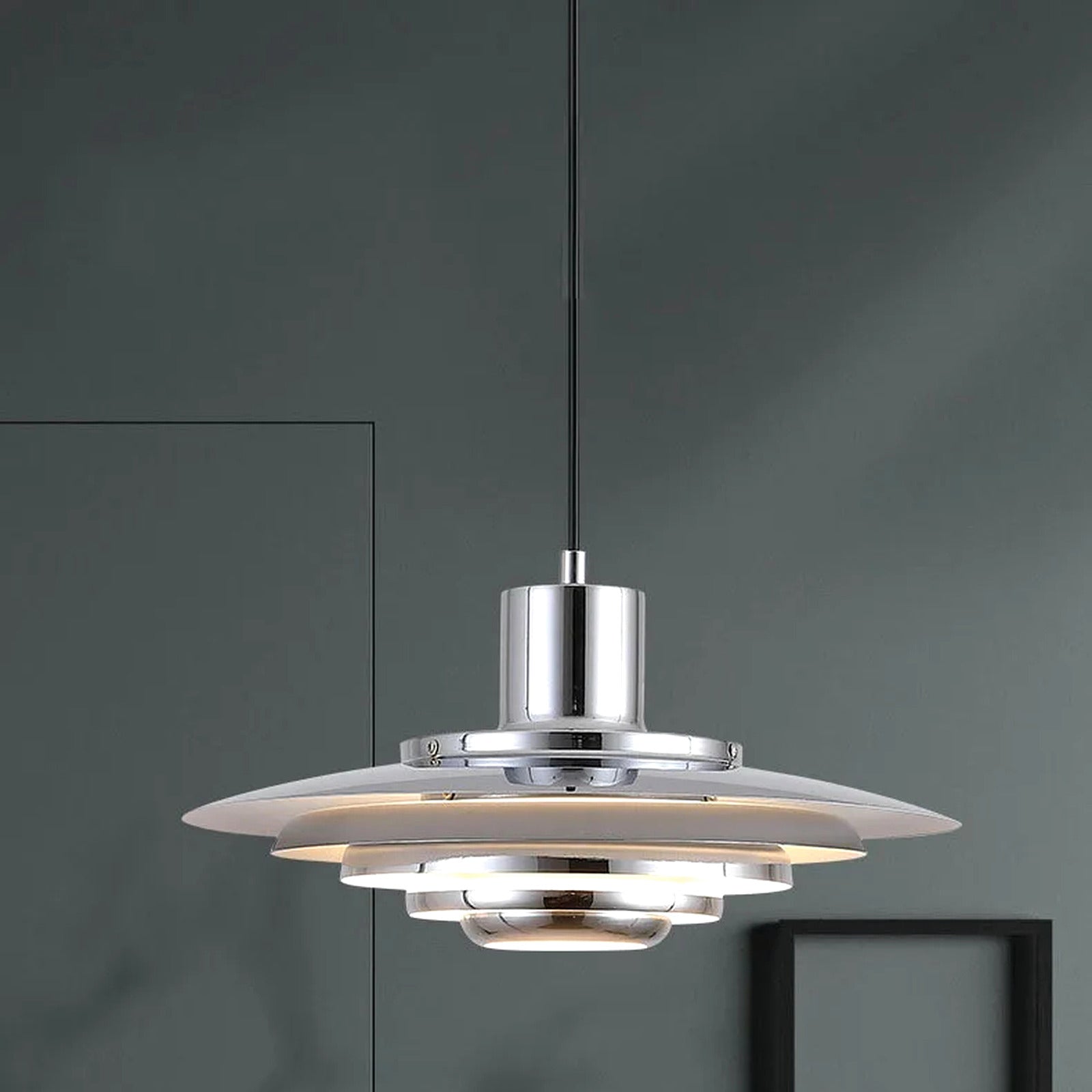 Närbild på Forma pendellampa i silver mot mörk vägg