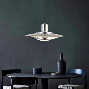 Forma pendellampa i silver över ett mörkt matbord