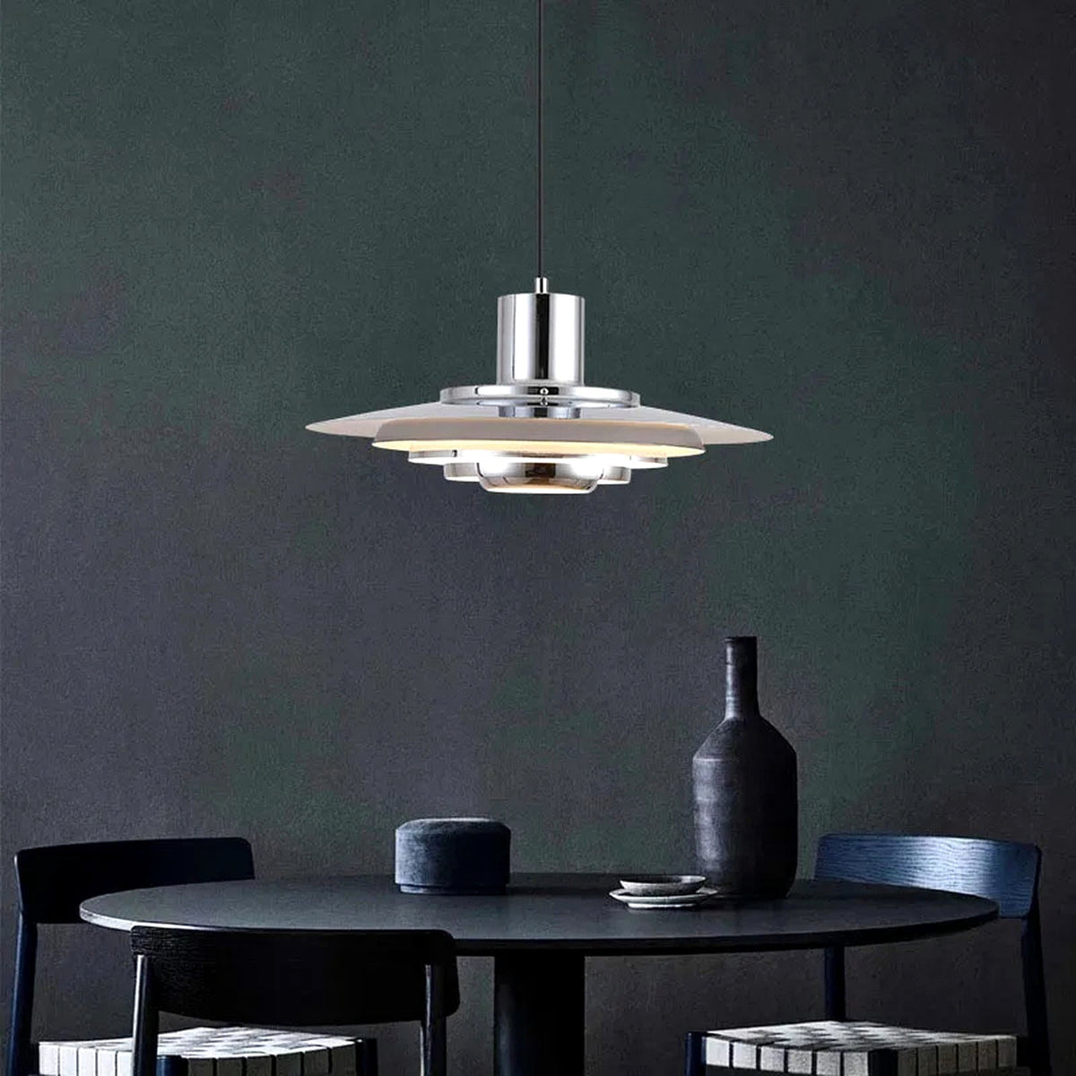 Forma pendellampa i silver över ett mörkt matbord